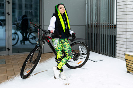 Woman Standing Next to Bike in Snowの写真素材