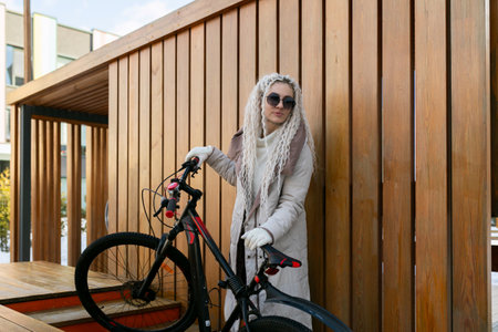 Woman Standing by Bike at Wooden Wallの写真素材
