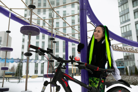 Woman Standing Next to Bike in the Snowの写真素材