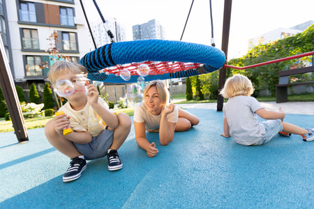 Mother Playing With Her Two Sons on a Sunny Day at the Playgroundの写真素材