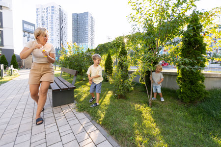Engaging Mother and Two Sons Enjoy Playful Afternoon at Urban Playground Surrounded by Greeneryの写真素材