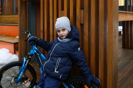 A little boy dressed in a snowsuit took his bicycle to the playgroundの写真素材