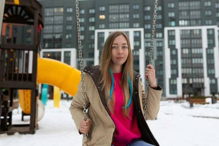 Woman Sitting on Swing in Snowの写真素材