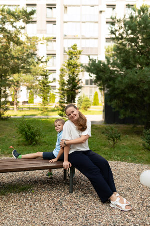 A joyful afternoon in the garden with mother and son enjoying their close-knit bond while relaxing on a wooden benchの写真素材