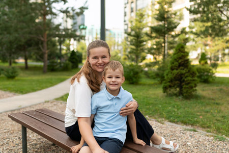A mother and son share a joyful moment on a sunny day in a park surrounded by greenery, enjoying each others company and loveの写真素材