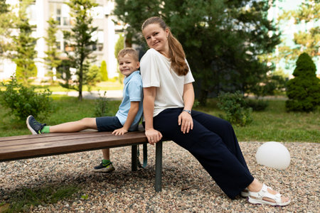 A joyful moment of mother and son sharing laughter and warmth on a bench in a sunny park during a leisurely afternoonの写真素材