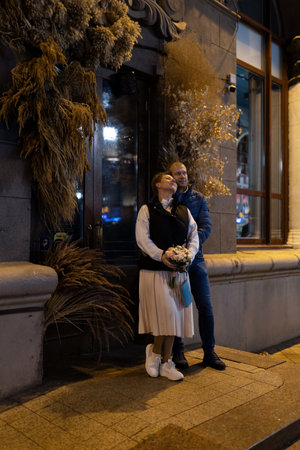 A couple strolls through the city at night, stopping to admire the viewの写真素材