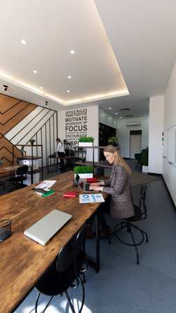 Modern workspace showcasing individuals engaged in collaborative activities and focused work in a bright office environmentの写真素材