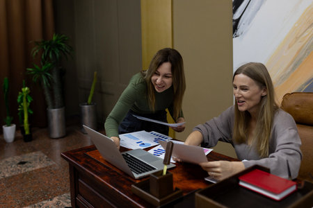 Colleagues sharing ideas while analyzing data in modern office space during daylight hours