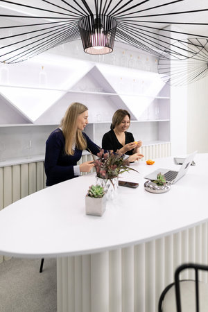 Two colleagues enjoy snacks and conversation in a modern office space during a work break in an urban settingの写真素材