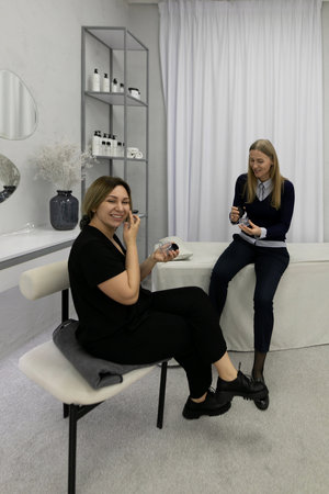 Clients enjoying a skincare consultation and makeup application at a modern beauty studioの写真素材