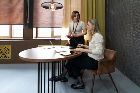 Business meeting discussing project details in modern office setting with warm lighting and stylish decorの写真素材