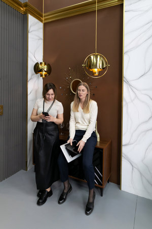 Two women engaged in conversation while sitting in a modern interior space decorated with elegant lightingの写真素材