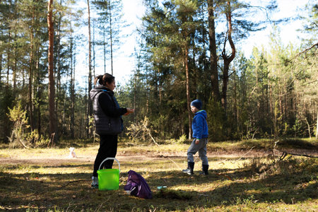 Mother and son explore a sunny forest, sharing a joyful moment while enjoying nature during a spring dayの写真素材