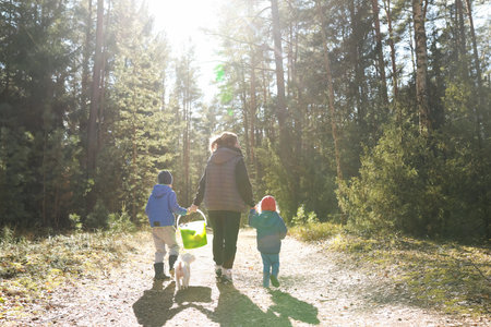 Family enjoys a sunny day walking in the forest with a dog and a basket in the late afternoonの写真素材