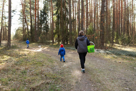 Family enjoying a nature walk in a forest during daytime with a child and a dogの写真素材
