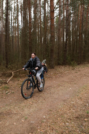 Family enjoys a bike ride on a forest trail during autumnの写真素材
