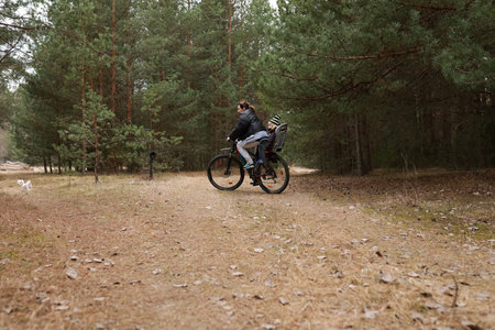 Cyclist enjoying a peaceful ride through a forest path on a cool autumn dayの写真素材