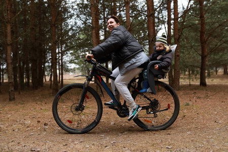 Father enjoys a bike ride with his child through a peaceful forest on a crisp autumn dayの写真素材
