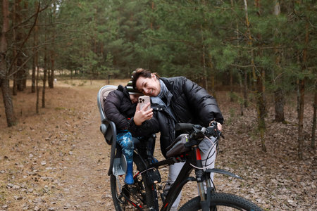 Family enjoys a joyful bike ride through the woods on a sunny afternoon while capturing a selfie togetherの写真素材