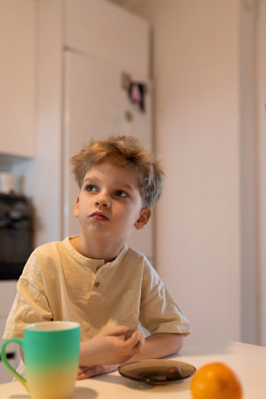 Young boy enjoys breakfast at home in a cozy kitchen on a sunny morningの写真素材