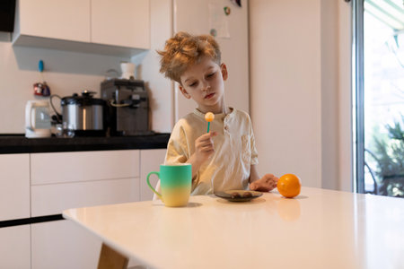 Child engaging in playful activity with colorful items in a bright kitchen during morning hoursの写真素材
