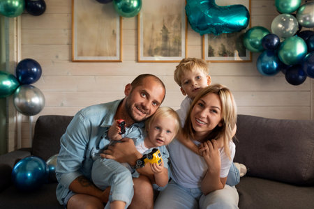 Family celebrates a special occasion at home with balloons and joyful expressions during a cozy afternoonの写真素材