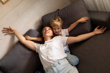 Mother and son enjoying playful afternoon on cozy sofa in living room at homeの写真素材