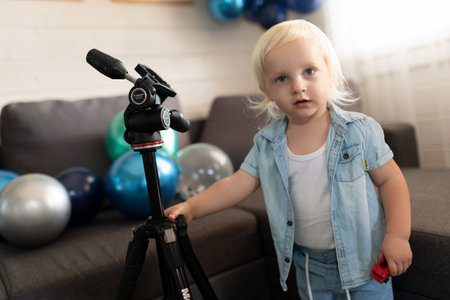 Child explores a tripod in a colorful indoor setting filled with balloons during a festive celebrationの写真素材