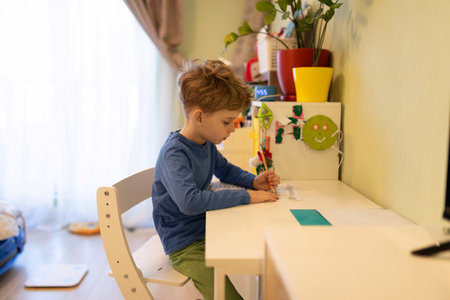 Child engaged in creative drawing activity at a cozy workspace in a bright room during the afternoonの写真素材