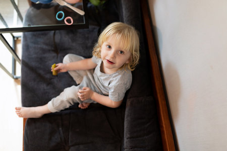 Child enjoys playtime on a cozy sofa in a bright living room during the afternoonの写真素材