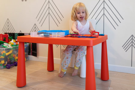 Child engages in creative play at a colorful table inside a bright room during the dayの写真素材