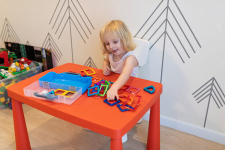 Child engages in creative play with colorful building shapes at a bright indoor activity spaceの写真素材