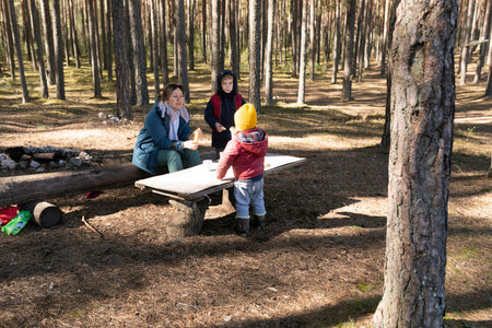 Family enjoying a picnic in a tranquil forest setting during a sunny afternoonの写真素材