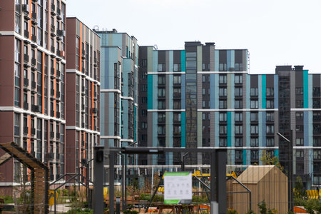 Modern high-rise apartment buildings in a vibrant residential area with gardens and playgrounds, providing options for rent and mortgageの写真素材