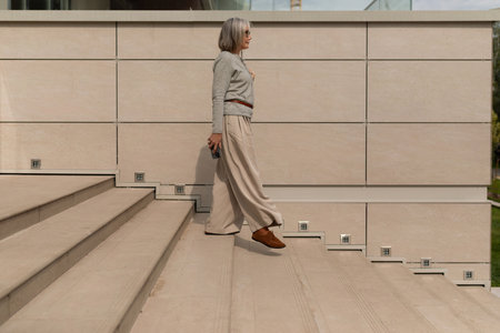 Woman walking down outdoor stairs in a modern setting during daylightの写真素材