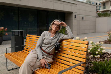 Middle-aged woman relaxing on a vibrant wooden bench in an urban setting during the afternoon