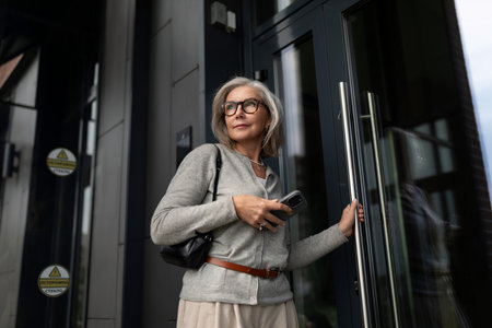 Sophisticated woman outside modern building preparing to enter during daylight hoursの写真素材