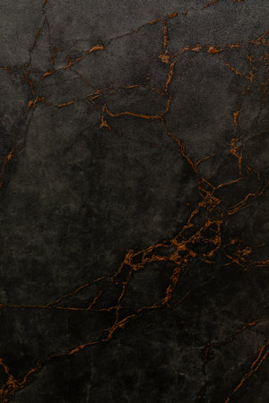 Dark marble surface with orange veins showcasing natural patterns for elegant design and decorの写真素材
