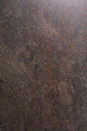 Dark textured stone surface with a unique pattern and natural variations observed in indoor lighting