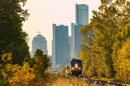 A passenger train leaves the city skyline behindの写真素材