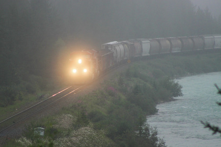Train Rolling Along River in Fog
