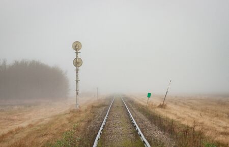 A pair of rails recede into the distant prairie fog