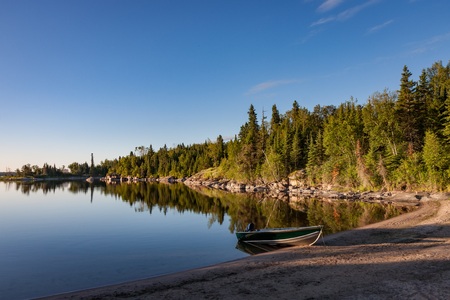Sunrise on Kutimit Lake. A boat is grounded on a beach in a peaceful cove.の写真素材