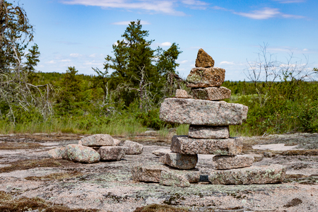 A large inukshuk stands on a broad rocky plain, part of the Canadian Shieldの写真素材