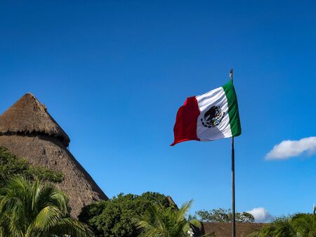 Mexican Flag and Thatched Roof Under a Blue Skyの写真素材