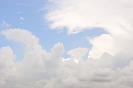 Fluffy white clouds floating downstream on the blue skyの写真素材