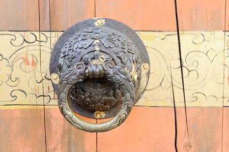Old dragon knocker on the red wooden door of Chinese temple