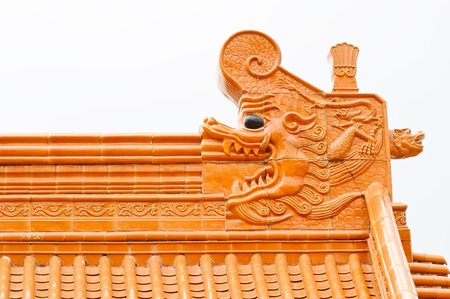 Orange dragon statue on top of Chinese temple roof.