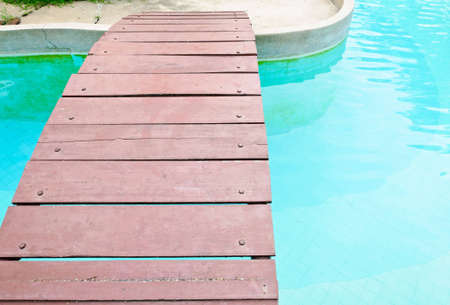 Wooden bridge on the clear pool of the hotel.